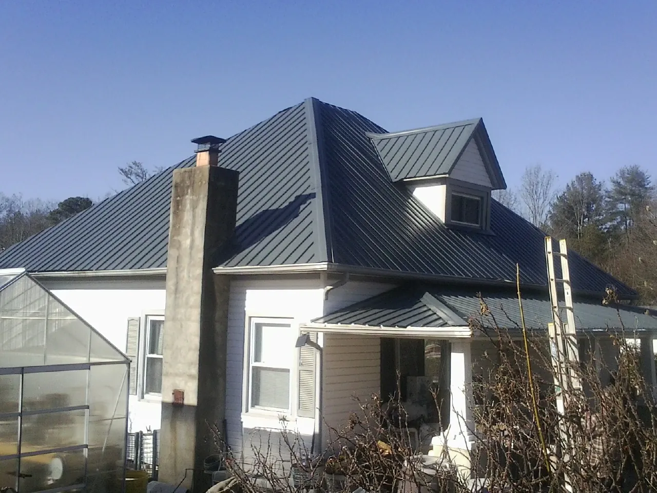 Dark blue standing seam metal roof on a white farmhouse with dormer — Slate & Tile Roof Repair by Roofing Brothers in Robersonville