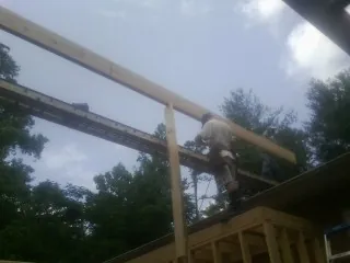 Carpenter setting a ridge beam over a new addition frame — Ice Dam Removal by Roofing Brothers in Robersonville