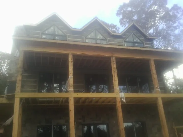 Dormers and porch framing on a large log home under construction — Roof Coating work by our crew in Robersonville