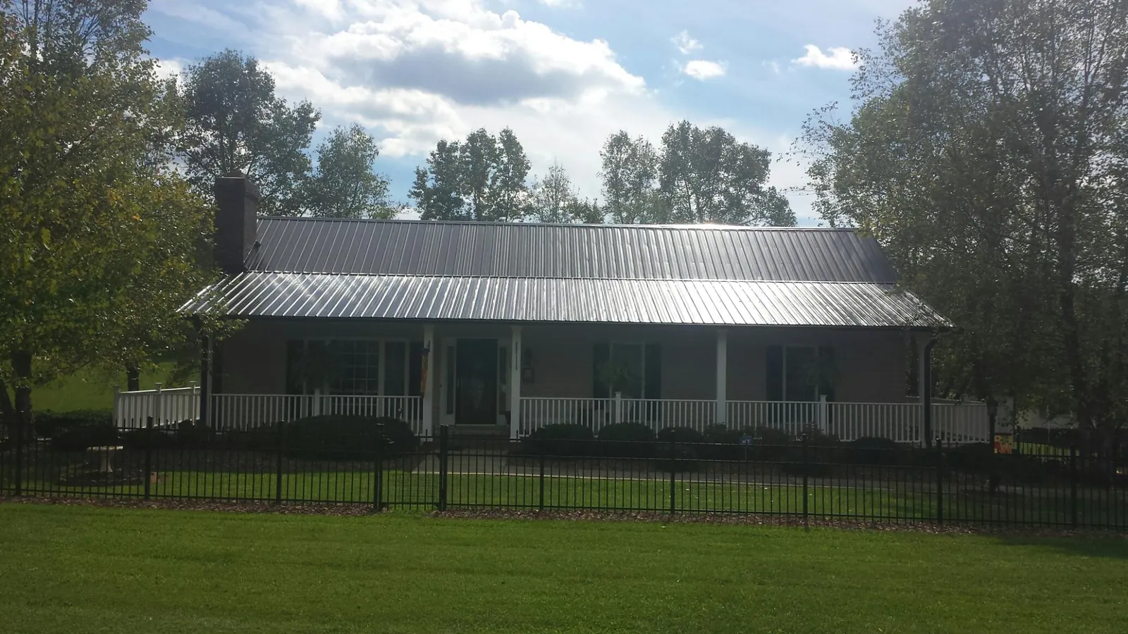 Gray metal roof on a brick ranch with a full width front porch — Gutter Guard Installation work by our crew in Robersonville