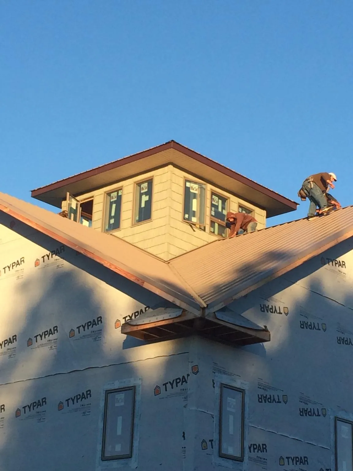 Roofers working around a rooftop cupola on a new metal roof at sunset — Roof Waterproofing in Robersonville by Roofing Brothers